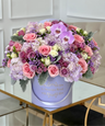 mixed flower arrangement of purple flowers in a lavender box vase