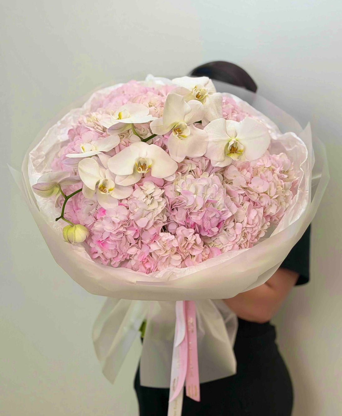 Luxury bouquet of blush pink hydrangeas and cascading white phalaenopsis orchids wrapped in elegant white paper
