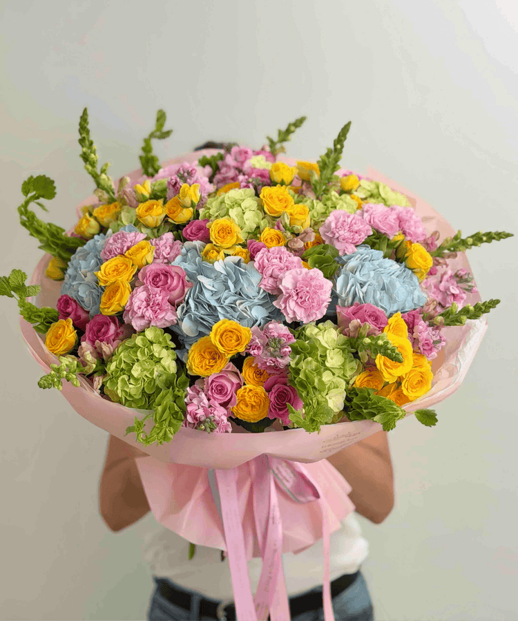 Ramo colorido con hortensias azules, rosas spray amarillas, rosas rosadas, claveles y flores de temporada.