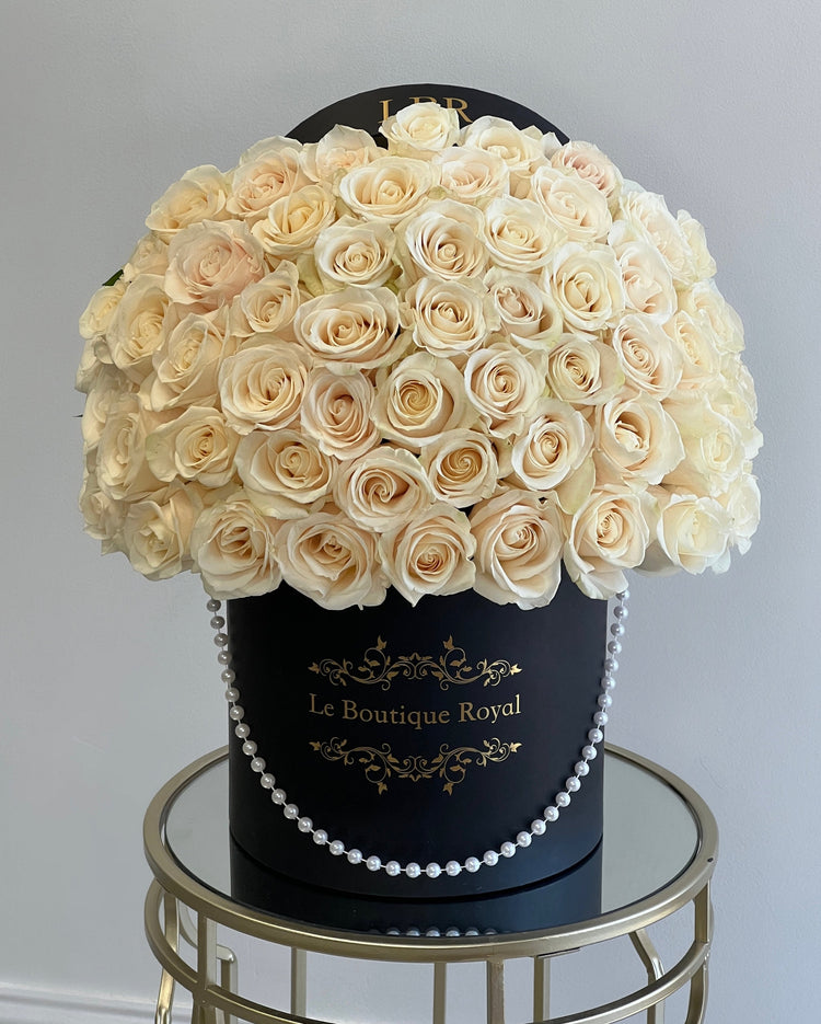 white roses in a black hat box with pearls