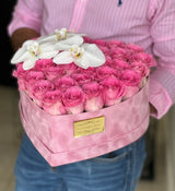 Rosas rosadas en una caja con forma de corazón con orquídeas encima