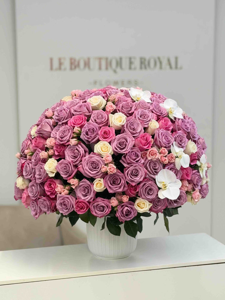 Luxury arrangement of lavender roses, pink spray roses, ivory roses, and white orchids in an elegant vase by Le Boutique Roya