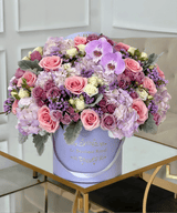 mixed flower arrangement of purple flowers in a lavender box vase