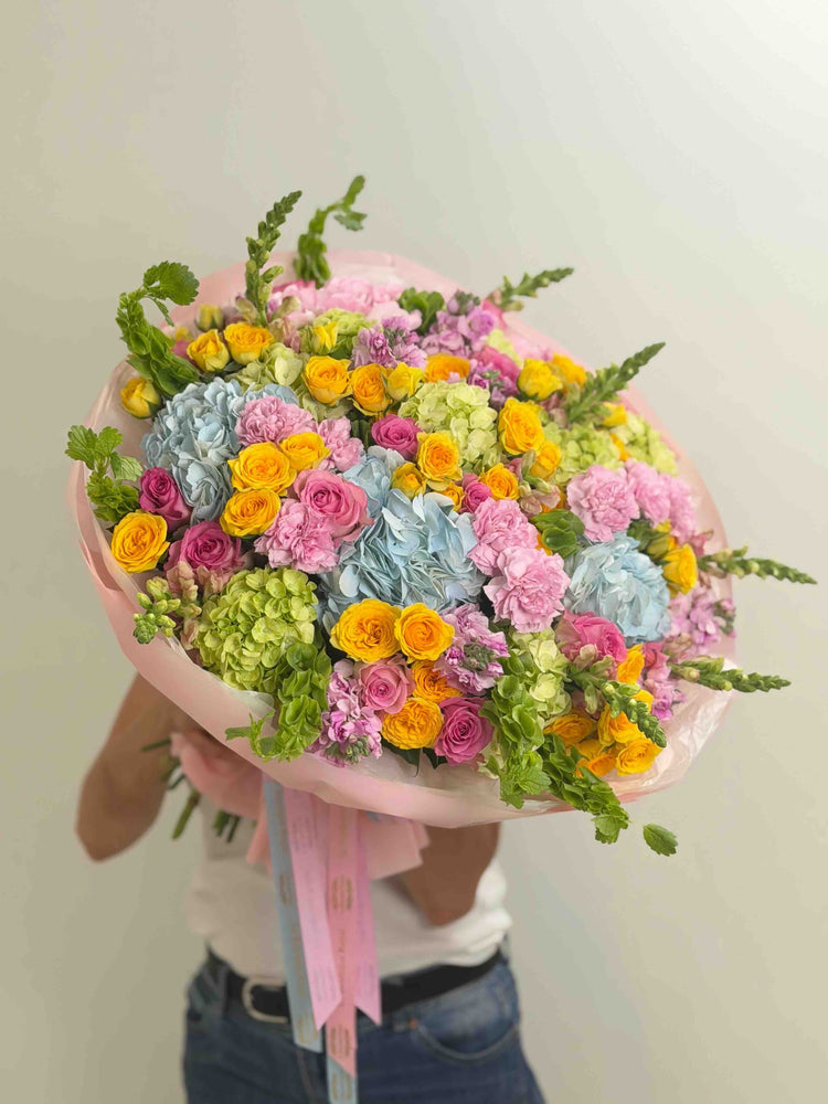 Ramo colorido con hortensias azules, rosas spray amarillas, rosas rosadas, claveles y flores de temporada.