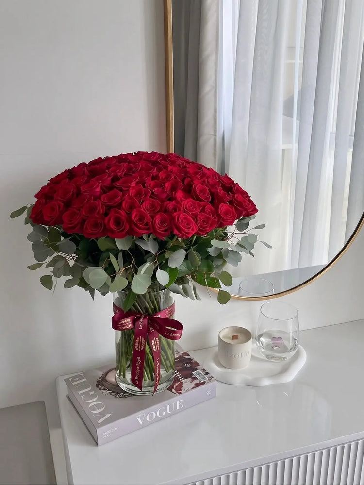 Grand red rose arrangement with eucalyptus in a glass vase by Le Boutique Royal